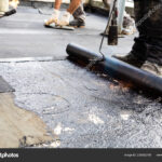 Flat roof installation. Heating and melting bitumen roofing felt.