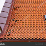 Damaged tile roof of a historical house with some missing roof tiles