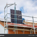 Lifting solar panels using pulley. Installing solar panels on a roof. Solar panels on roof.  Workers installing solar cells.
